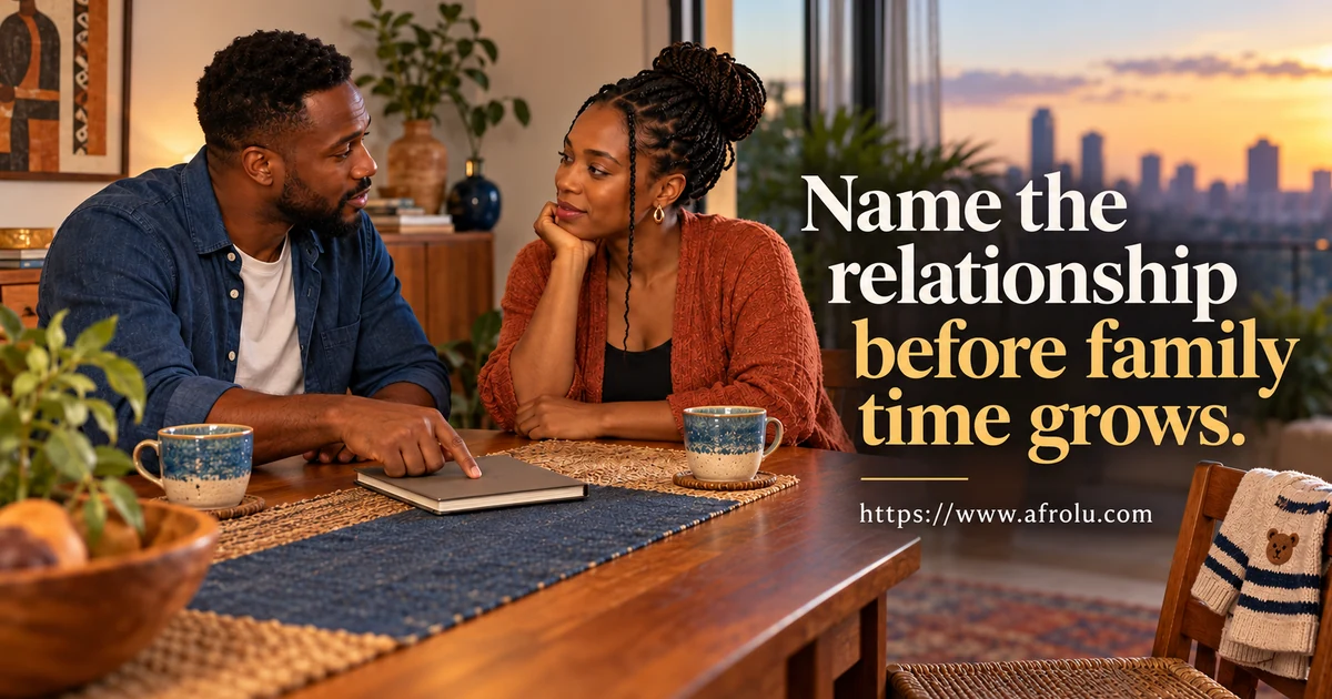 Two adult Black people talk at a dining table while one points to a closed planner.