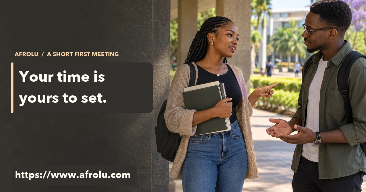 An adult student holding study books talks with another adult under a public campus walkway.