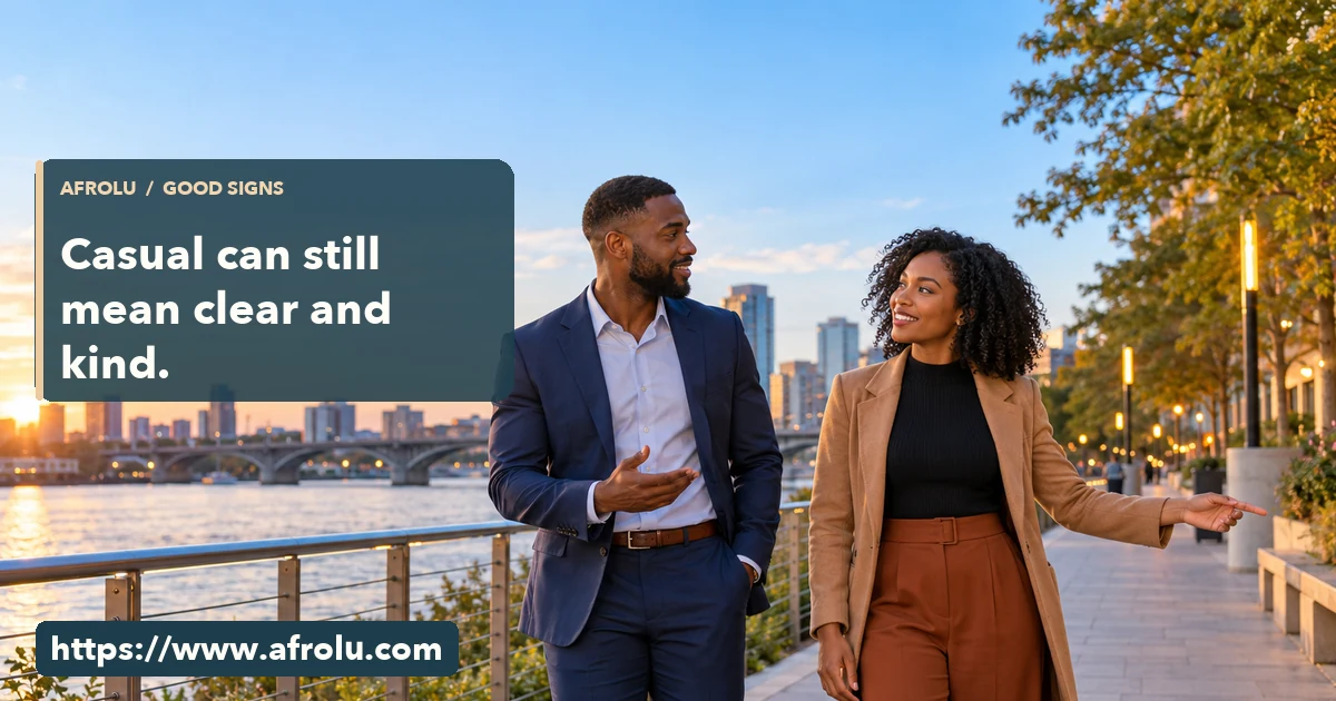 Two adult Black professionals talk while walking a public riverside path and agree on which way to go.