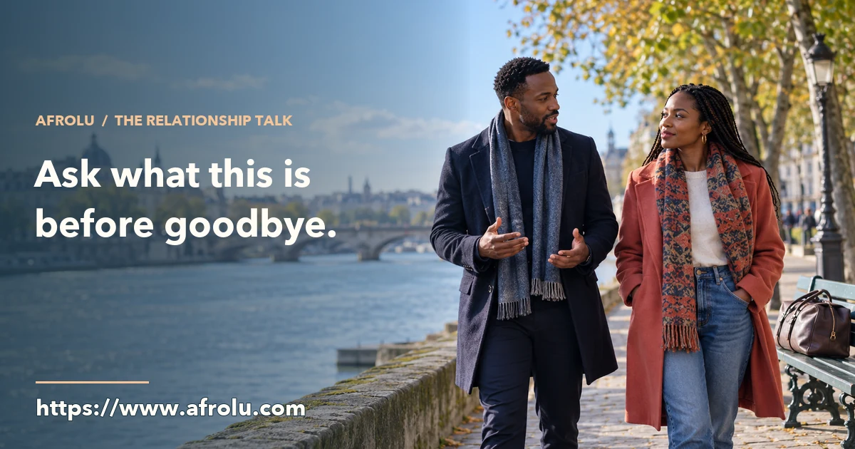 Two adults talk while walking beside a river during a weekend visit, with a travel bag on a nearby bench.