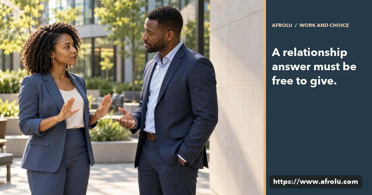 Two adult coworkers speak in a public office courtyard with space between them.