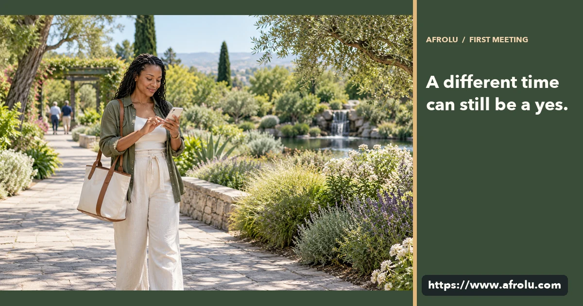 An adult traveler checks a phone beside a public garden path before a first meeting.
