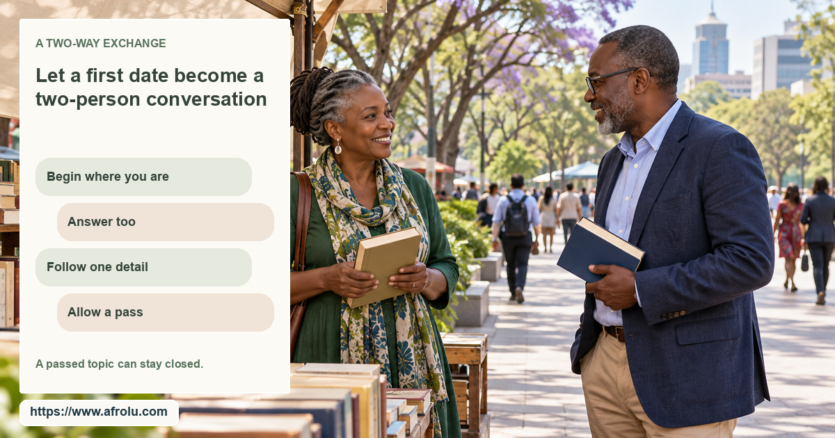 Two adults talk beside a public outdoor bookstall, each holding a different book with an open pedestrian path behind them.