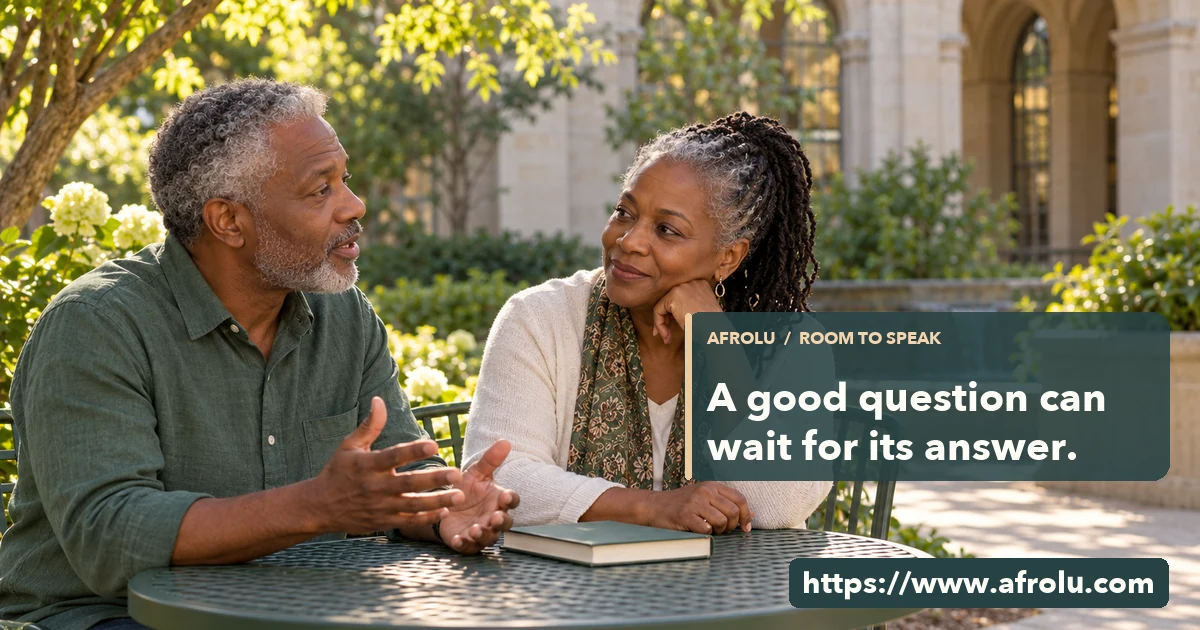 Two adults speak and listen at a public library garden table.