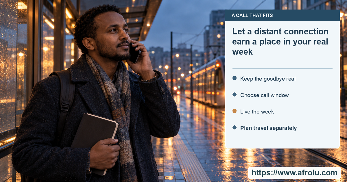 An adult on a phone call at a rainy city tram platform holds a closed travel notebook in the other hand.