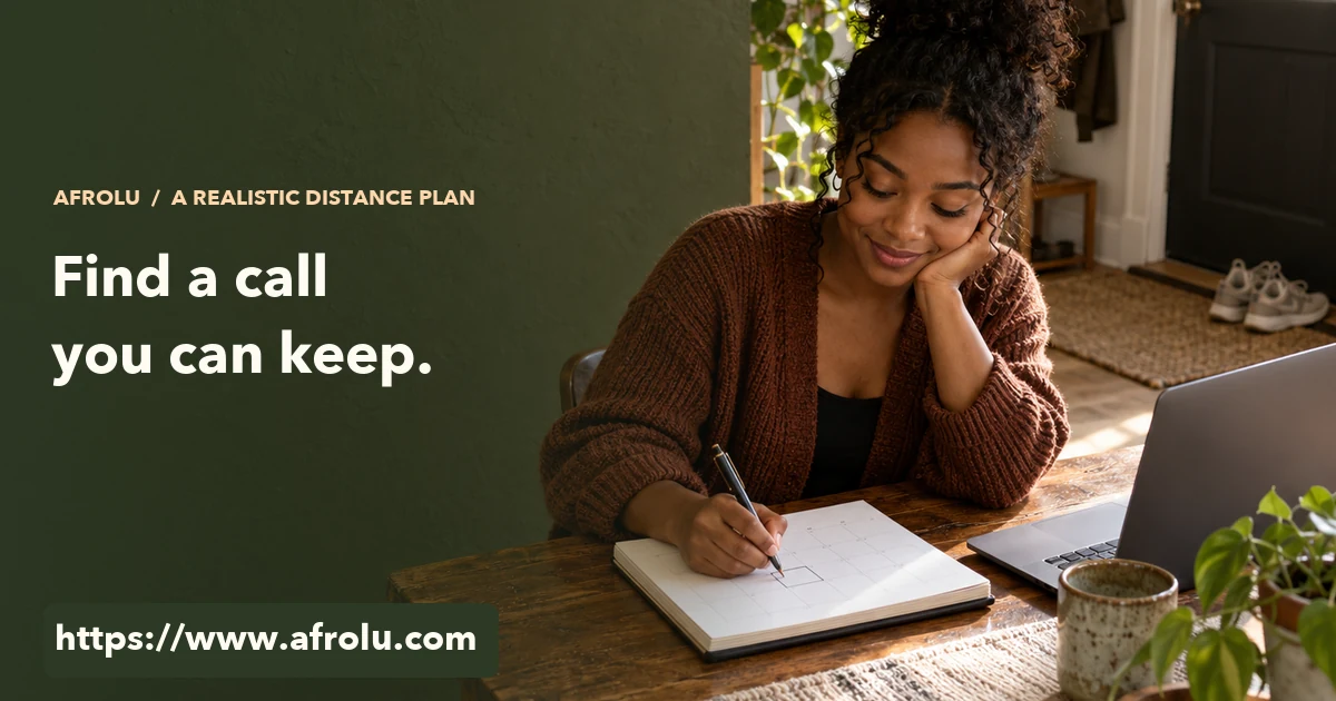 An adult marks a paper calendar beside a closed laptop at a home table.