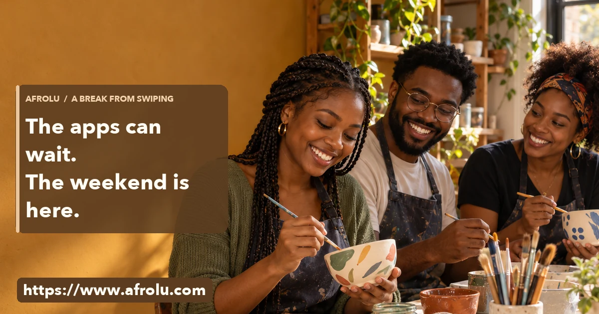 Three adult Black students paint ceramics together at a sunny community workshop.
